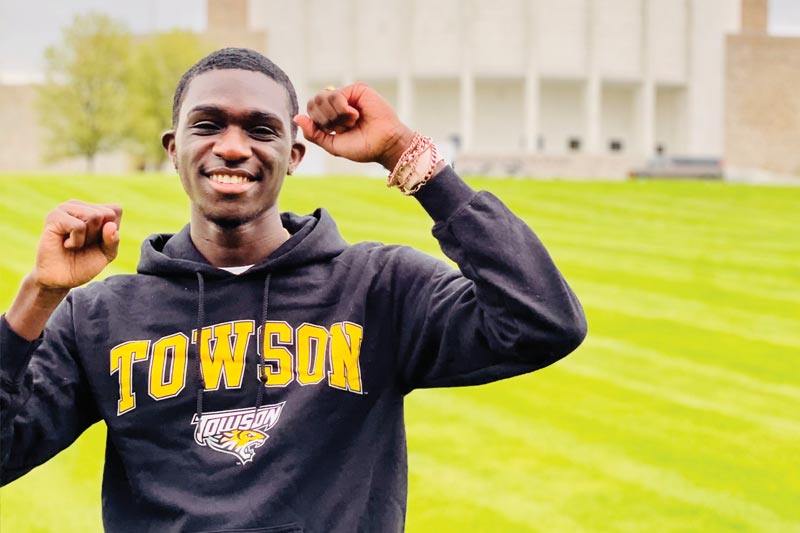 MHS student wearing Towson College sweatshirt in front of Founder's Hall building