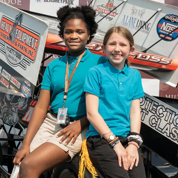 MHS students posing by race car at a World of Outlaws event