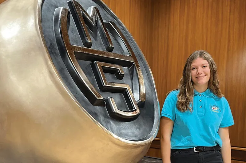 MHS student standing next to ring sculpture