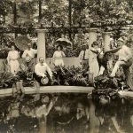 a group of people sitting on a bench near a pond