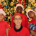 a group of kids in red shirts and santa hats