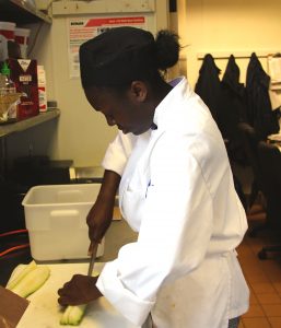 a person in a white coat cutting food
