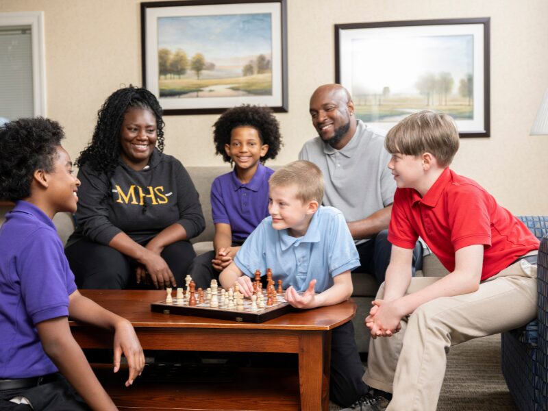 housparents teaching students how to play chess