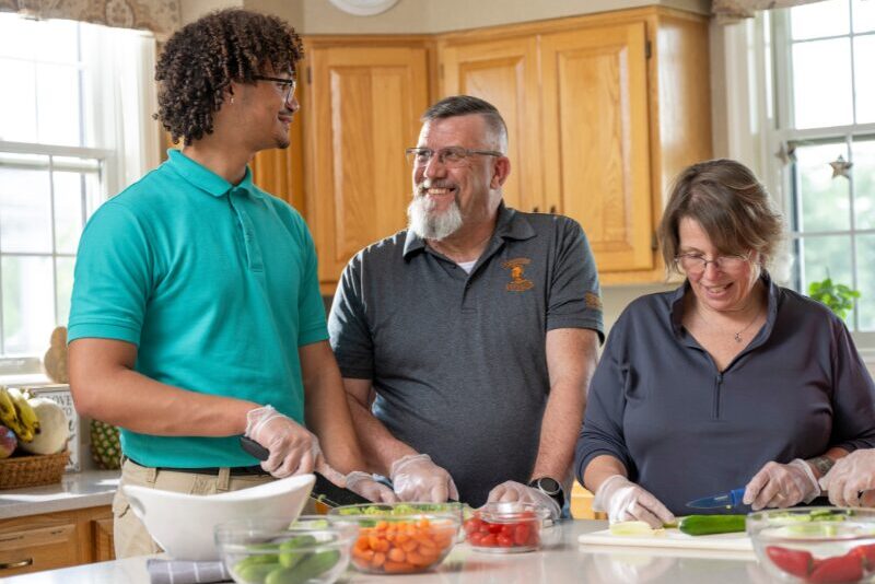 MHS houseparents cooking dinner with one of their students