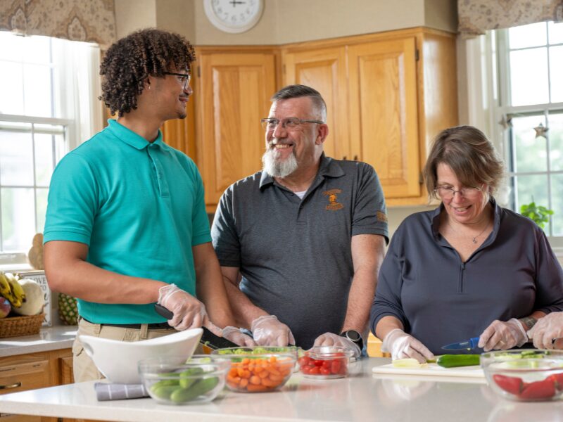 MHS houseparents cooking dinner with one of their students