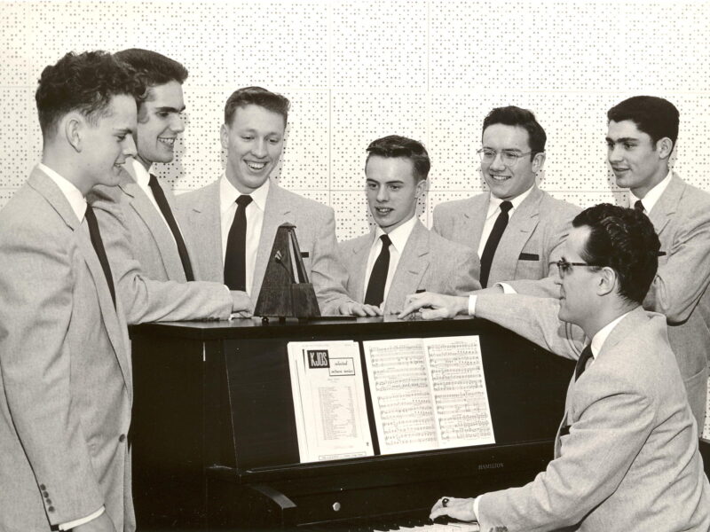 Students singing around a piano, music through the years