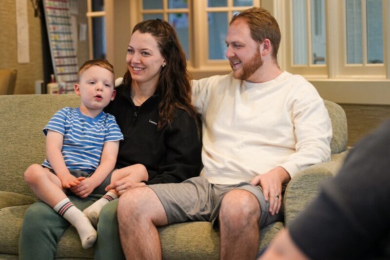 Houseparents Lauren and Avery White sitting on the couch with their toddler
