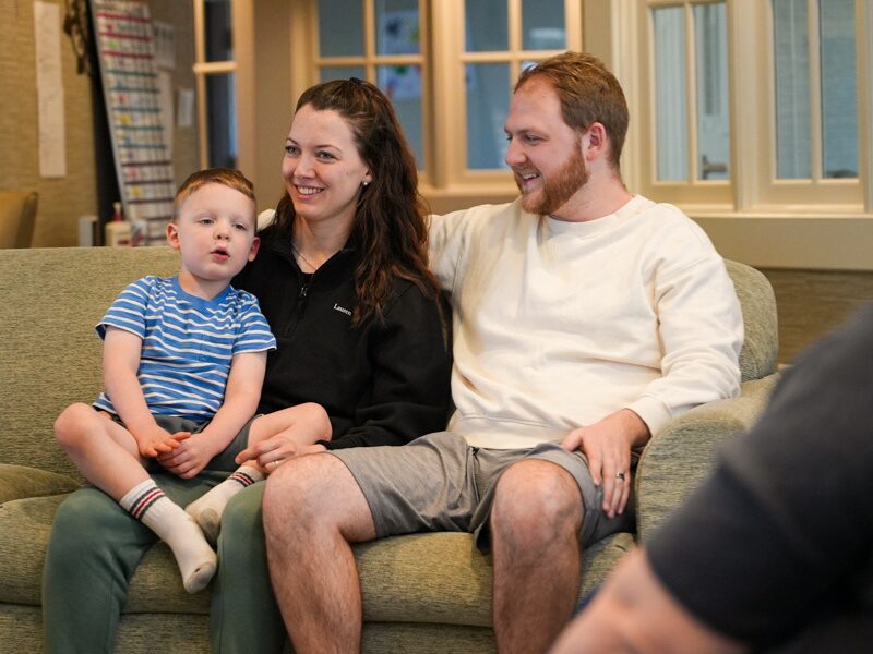 Houseparents Lauren and Avery White sitting on the couch with their toddler