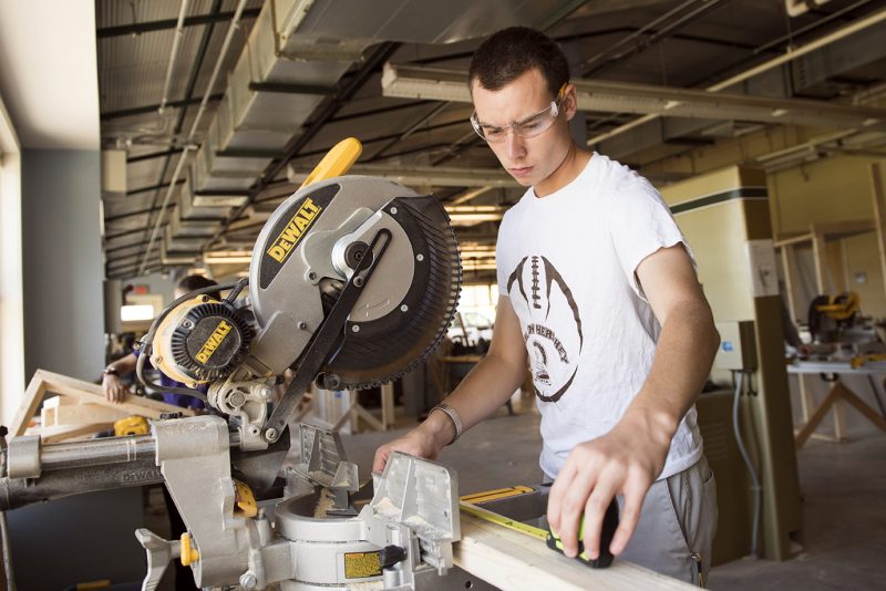 A Milton Hershey School student measures a piece of wood on the table saw during his Construction/Carpentry Career and Technical Education class.