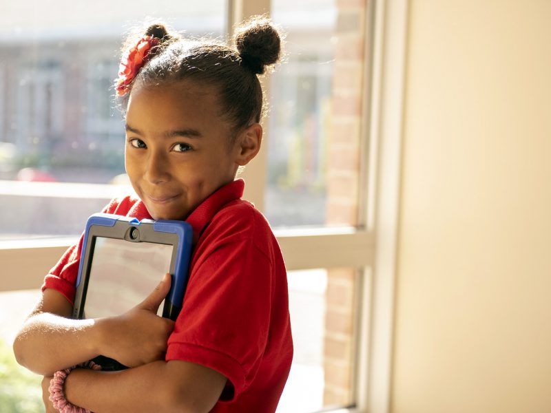 A Milton Hershey School elementary student holds her tablet outside of class.