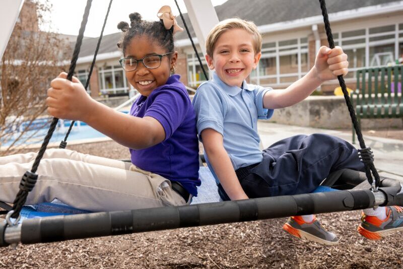 elementary students playing on a swing