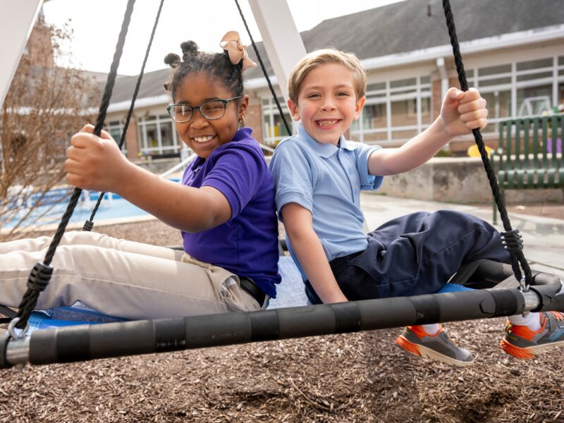 elementary students playing on a swing
