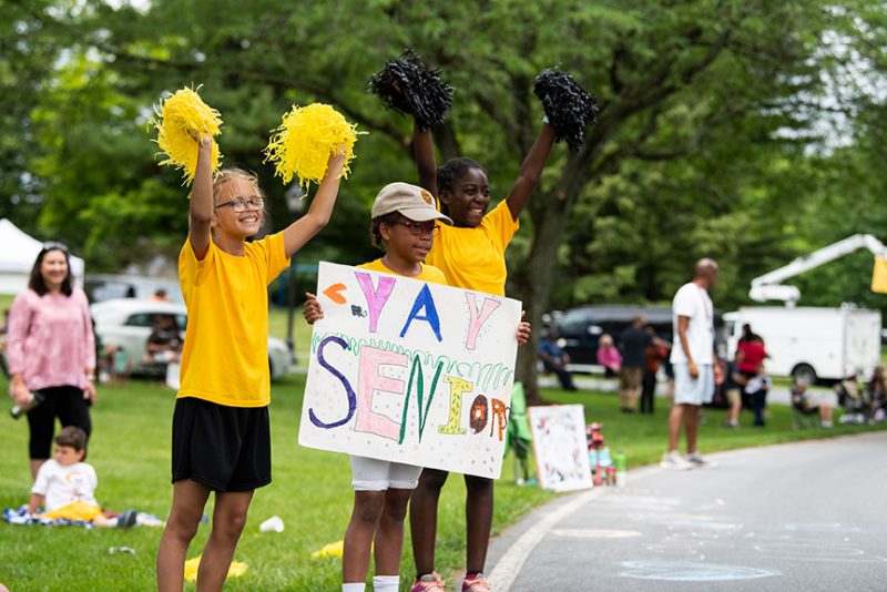 a group of young children holding pom poms and a sign