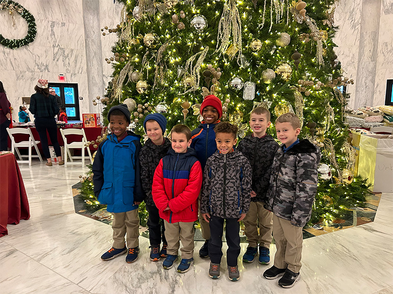 a group of children standing in front of a christmas tree