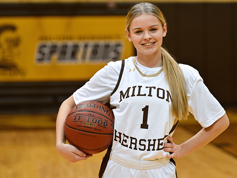 Milton Hershey School girls' basketball player poses with a basketball in hand.