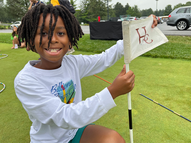 A Milton Hershey School student holds a Hershey Country Club flag.