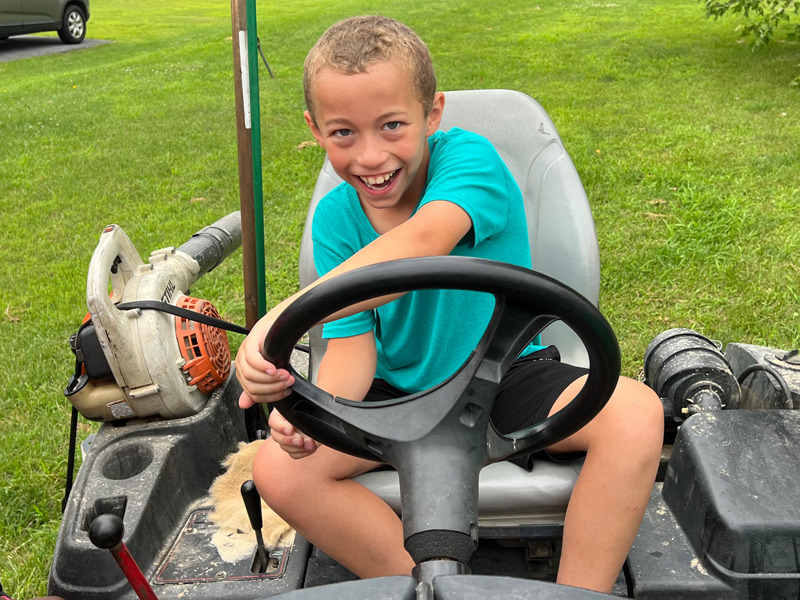 A Milton Hershey School student sits on a Hershey Country Club tractor.
