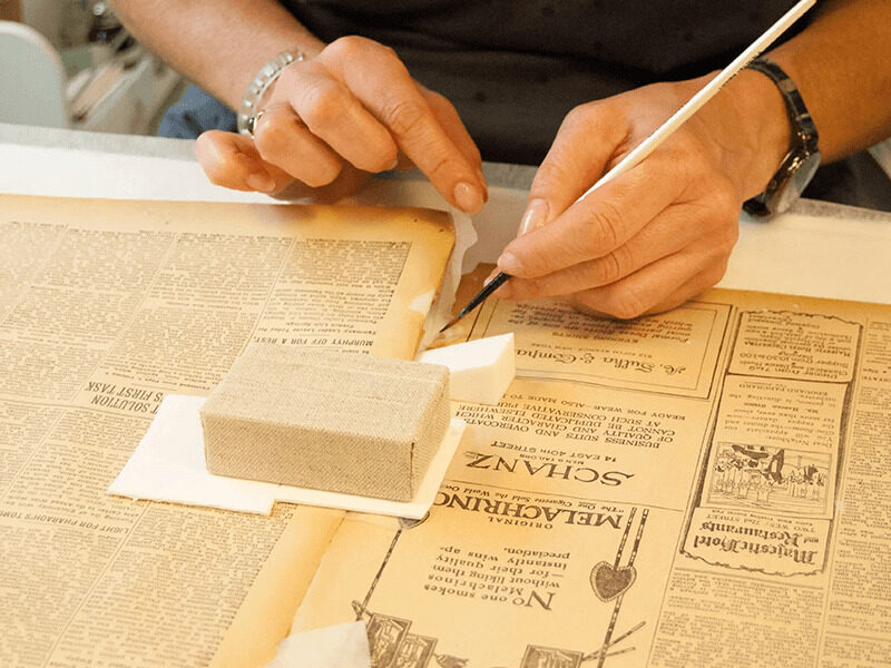 Milton Hershey School staff conserving historic newspaper clipping.
