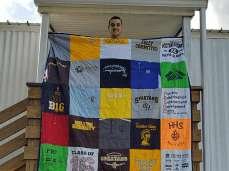 Milton Hershey School alumnus, Omar Barrada stands with a blanket representing his time at MHS.
