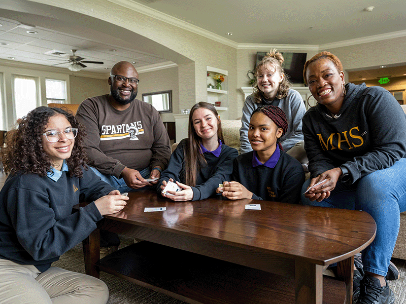 Milton Hershey School students sit around a coffee table with their houseparents.