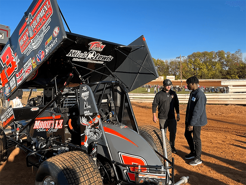 Milton Hershey School student works with World of Outlaws pit crew.