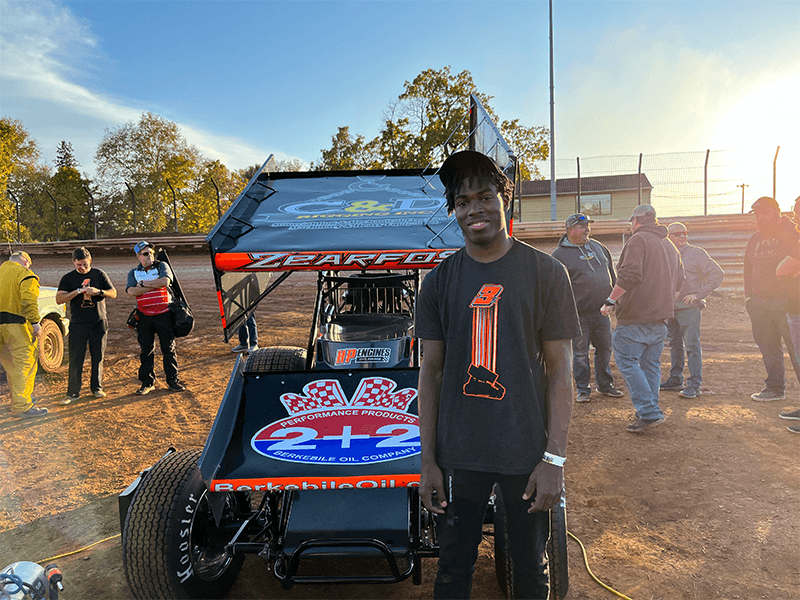 Milton Hershey School student stands with World of Outlaws race car.