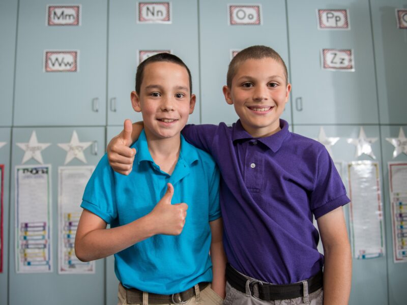 two children standing in front of lockers