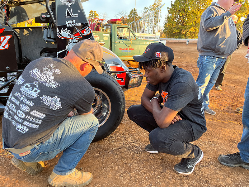 Rayshawn Shuler ’23, Milton Hershey School alumnus, inspects car tire at Williams Grove Speedway.