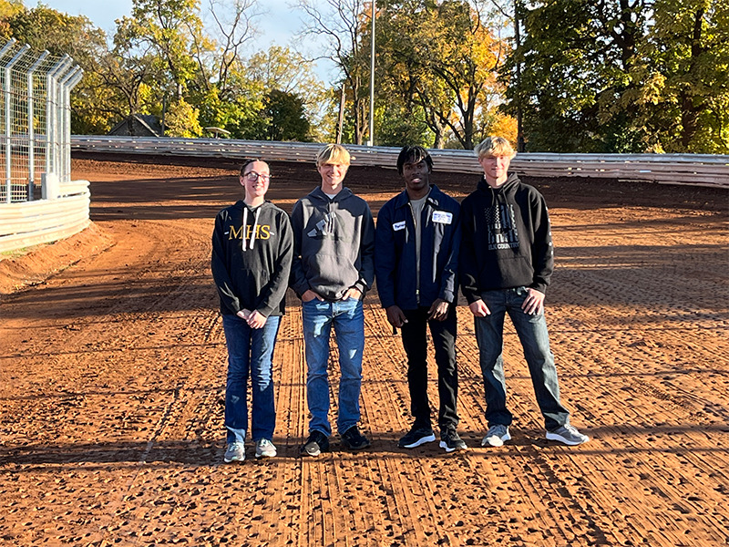Rayshawn Shuler ’23, Milton Hershey School alumnus, stands with other MHS students at Williams Grove Speedway.