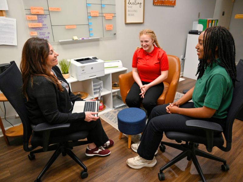 MHS TLA sitting in her office with two female students